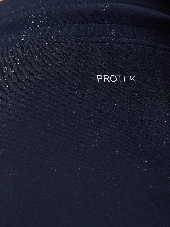 Close-up of navy Flex Shorts fabric with PROTEK branding and water droplets
