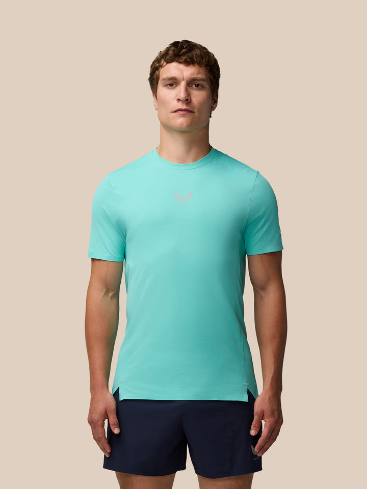 Male model in light aqua Zone Training T-Shirt with navy shorts front view on a beige background
