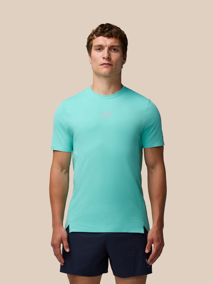 Male model in light aqua Zone Training T-Shirt with navy shorts front view on a beige background