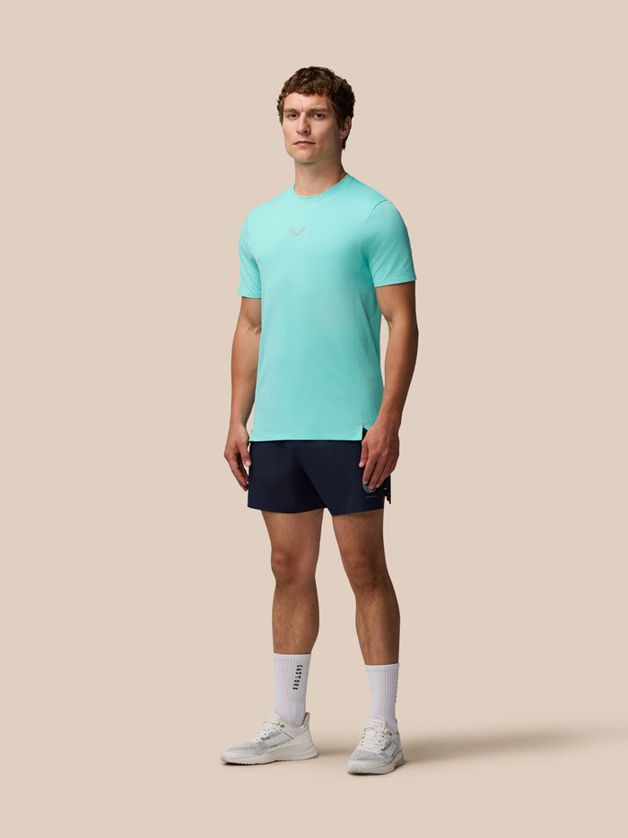 Model wearing Zone Training T-Shirt in light aqua with navy shorts, standing against a beige background.
