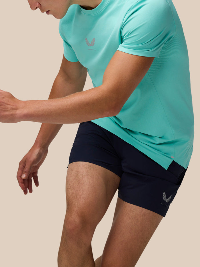 Close-up side view of model wearing light aqua Zone Training T-Shirt with navy shorts.