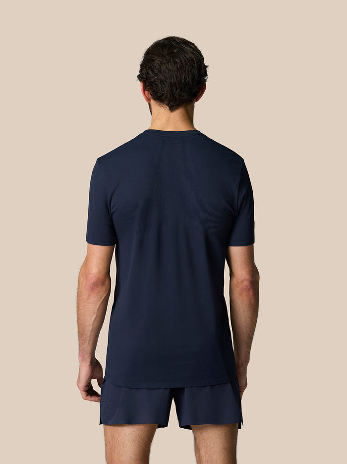 Back view of a man in Midnight Navy Zone Training T-Shirt and matching shorts on a beige background