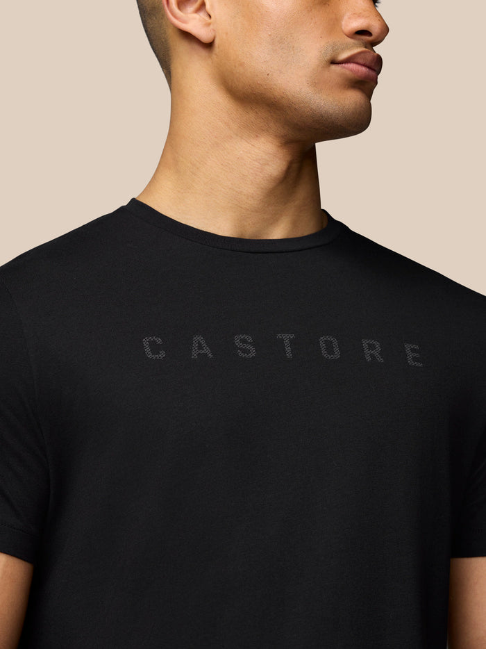 Close up of black graphic T shirt showing the subtle chest logo on a model.
