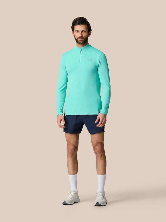 Full-body shot of a man wearing light aqua Zone Training 1/4 Zip Top with long sleeves and stand-up collar
