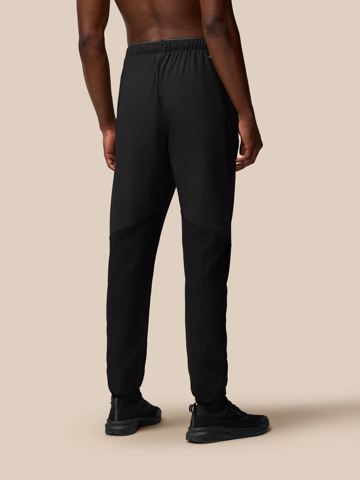 Back view of a man wearing black Flex Winterised Woven Joggers showing the elastic waist and textured lower leg panels.