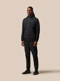 Full body view of a man wearing black Flex Winterised Woven Joggers with a black jacket.