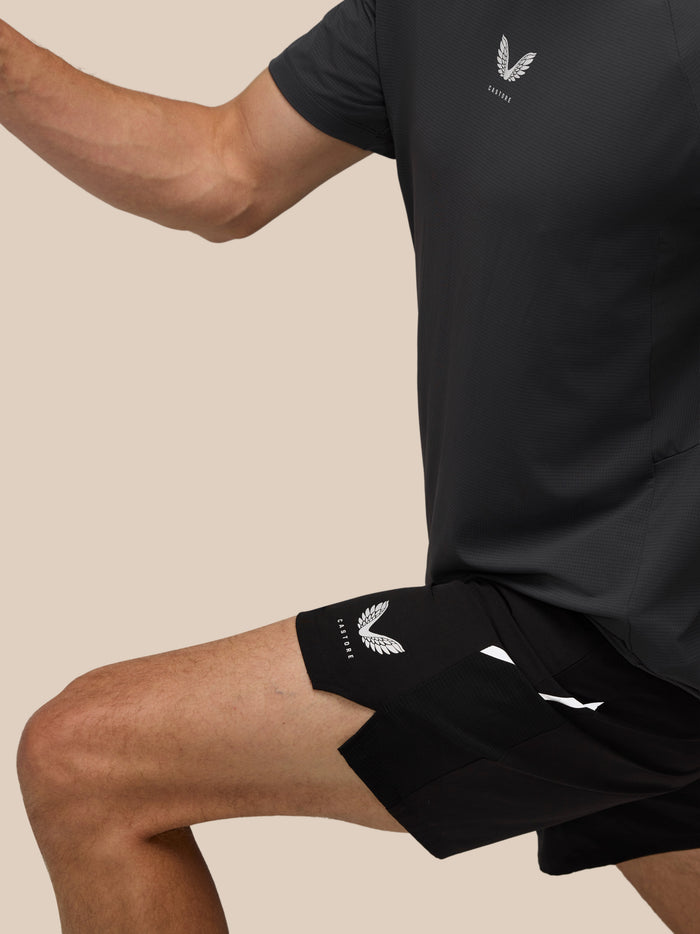 Side view of a man in black Apex Training 6 Inch Shorts with Castore logo on the leg and textured fabric