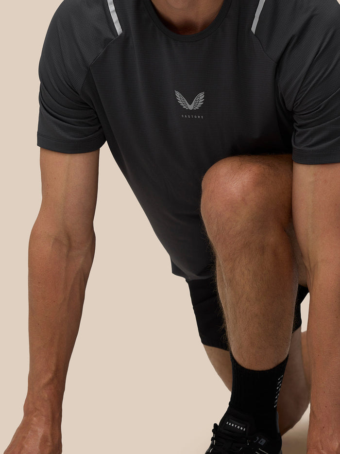 Man wearing gunmetal Apex Training T Shirt with Castore logo on the chest and reflective shoulder details.