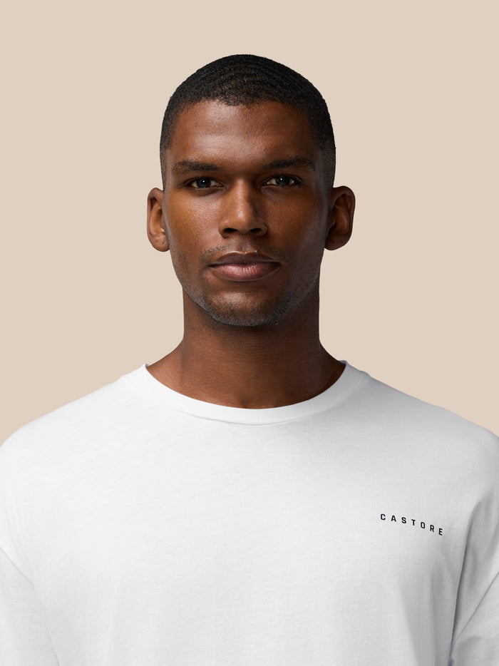 Male model wearing a white Flex Cotton T-shirt with round neckline and black Castore logo on the chest
