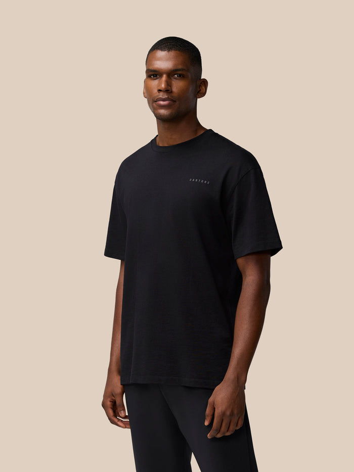 Three-quarter view of a male model in a blackFlex Cotton T Shirt with a round neckline and black shorts.