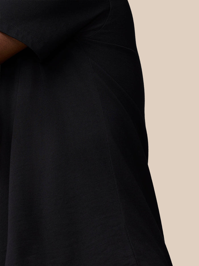 Close-up of black Flex Cotton T Shirt fabric showing knit texture and side seam against a beige background