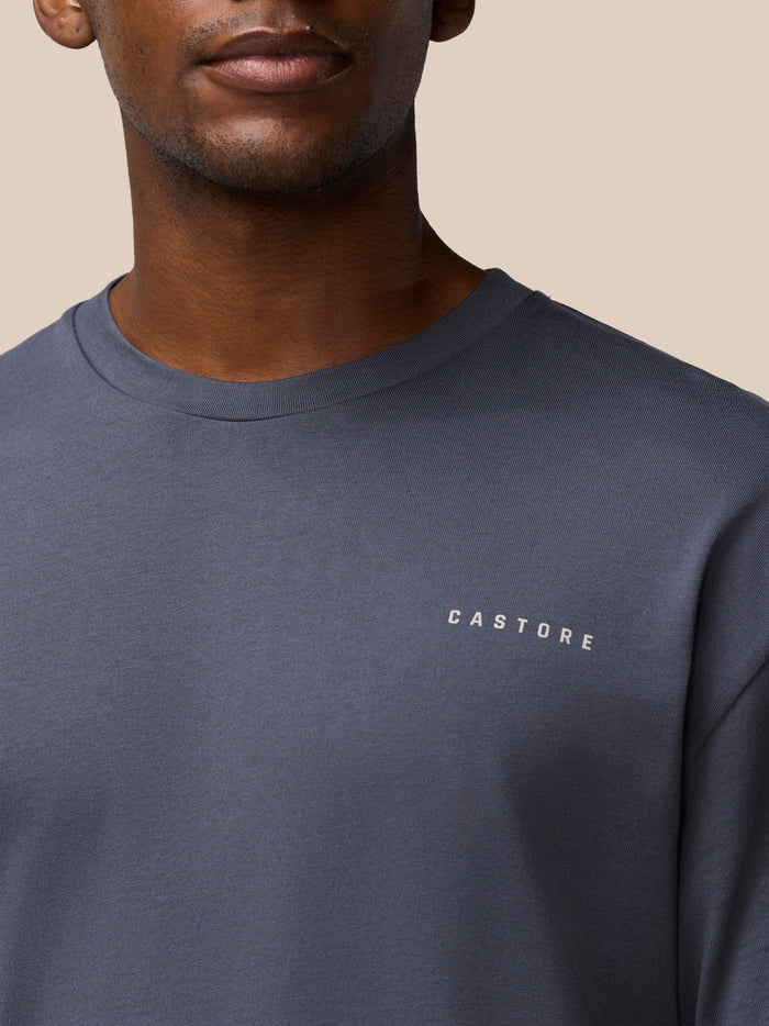 Close-up of a pewter Castore T-shirt on a model, highlighting the round neckline and small chest logo.