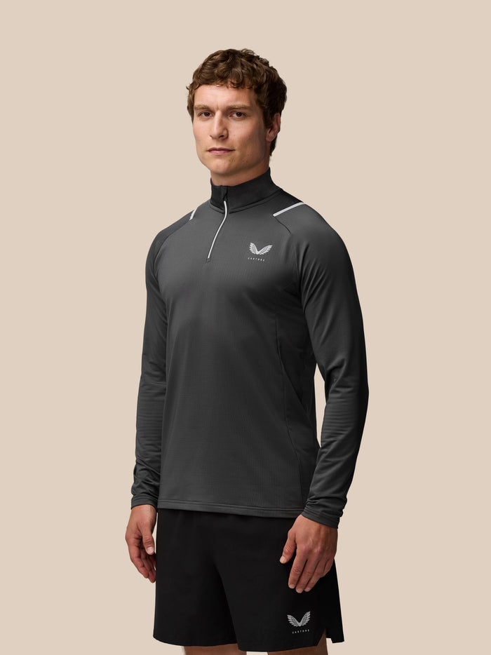 Male model wearing charcoal Apex Training Winterised quarter zip top with high collar and reflective shoulder details.