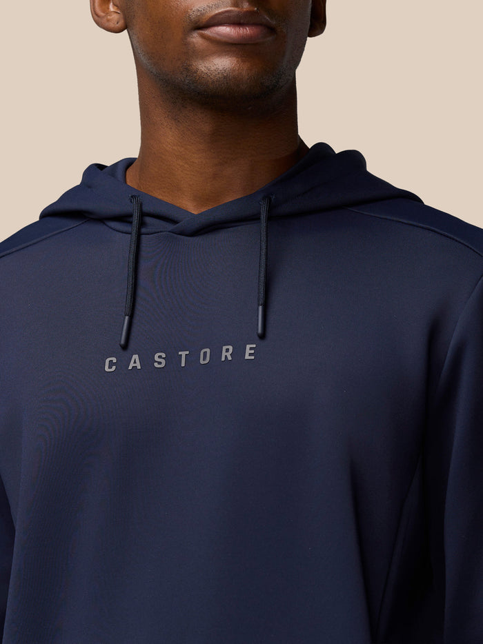 Close-up of navy hoodie showing Castore wordmark centered on the chest and hood drawstrings.