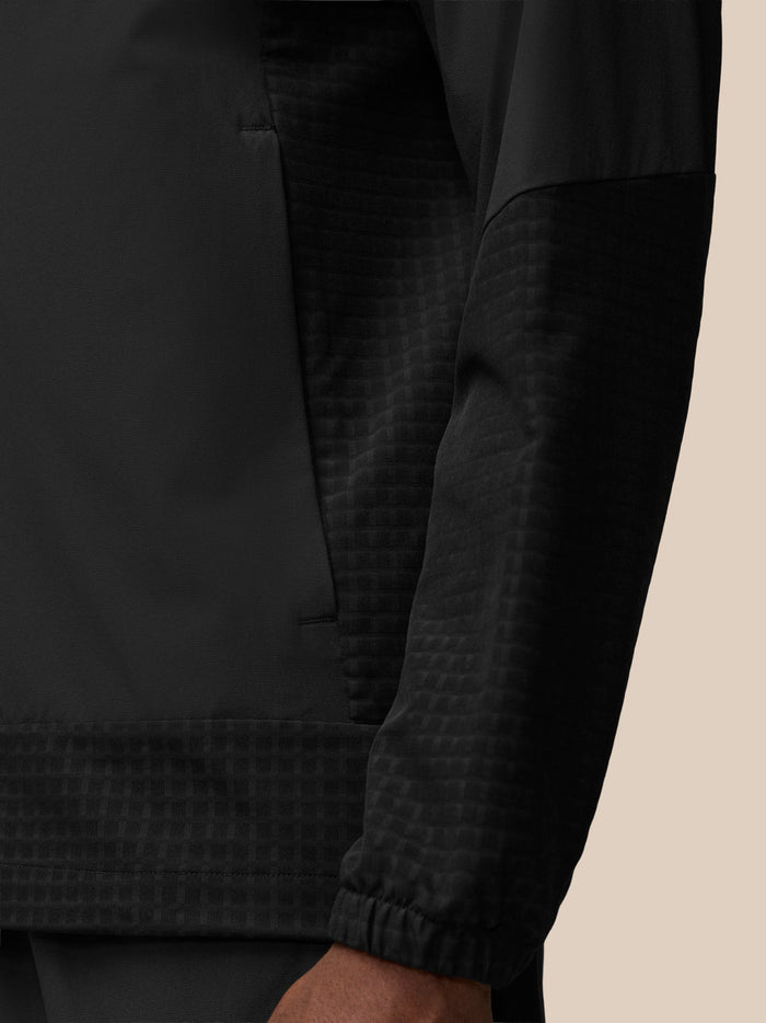 Close-up of black Flex Winterised Woven Jacket showing a textured grid pattern on the lower body and cuff