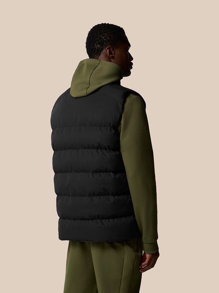 Back view of a black heavyweight padded gilet worn over an olive green hoodie