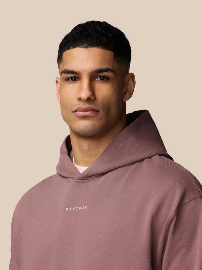 Portrait of a male model wearing a mauve hoodie with hood up