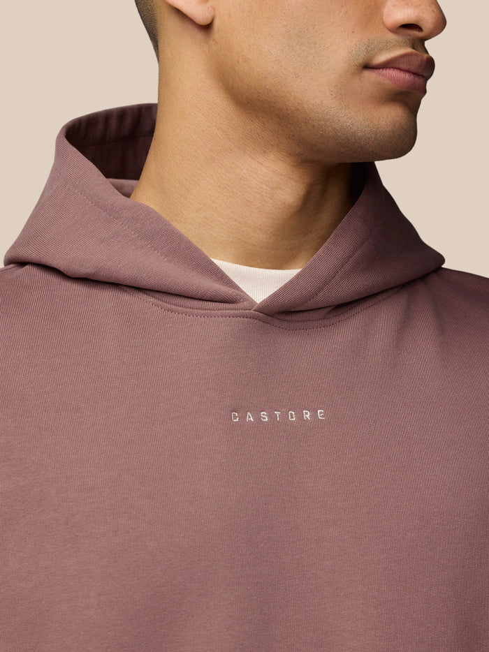 Close up of mauve hoodie fabric around the hood with a subtle Castore logo on the chest