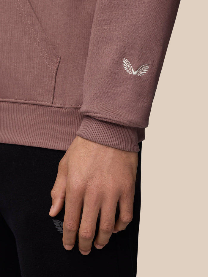 Sleeve detail of mauve hoodie showing white wing logo and ribbed cuff