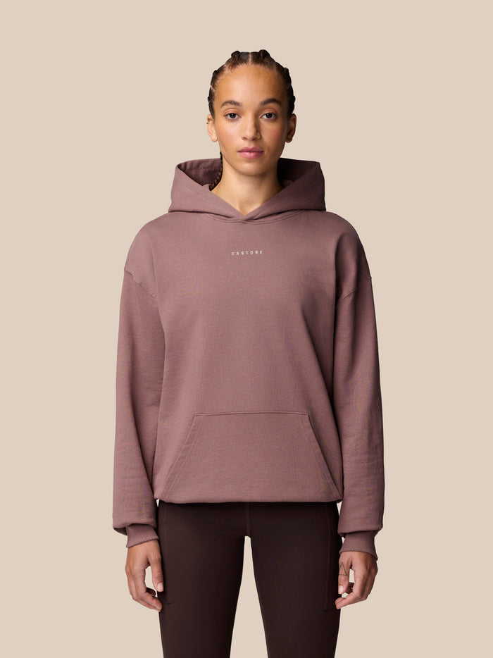 Female model wearing mauve Adapt Lifestyle Hoodie with hood down and front pocket.