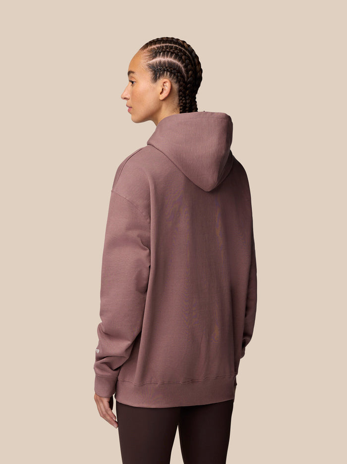 Back view of a model wearing a mauve Adapt Lifestyle Hoodie with the hood down