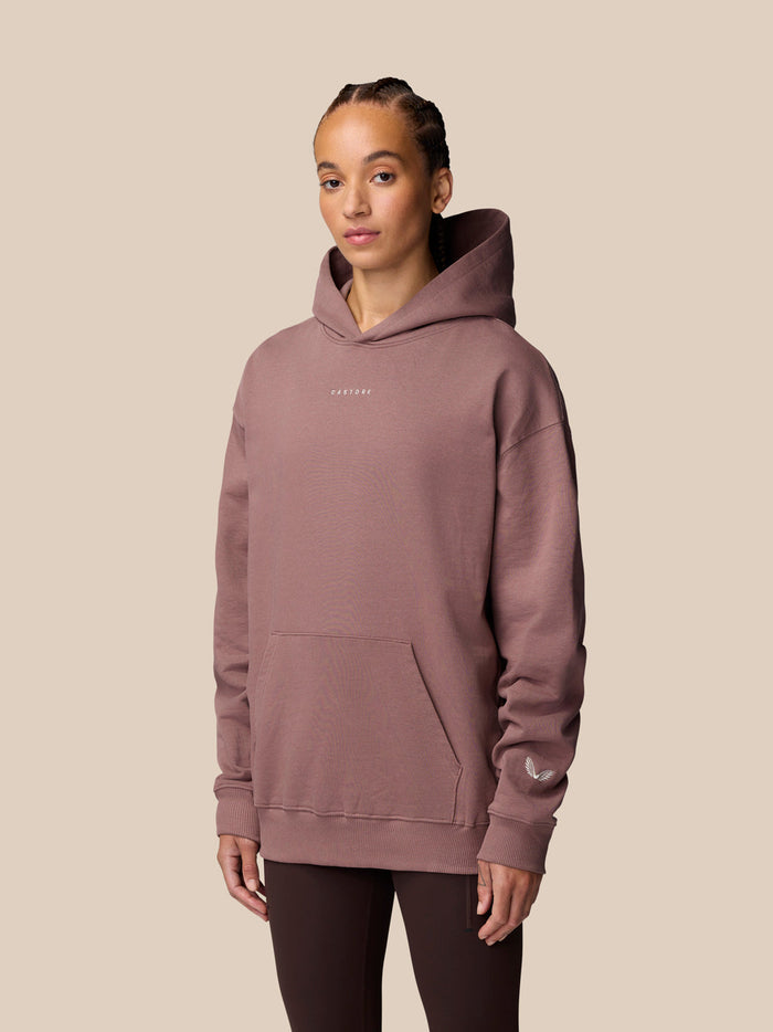 Front three quarter view of a model in mauve Adapt Lifestyle Hoodie with hood up and pocket.