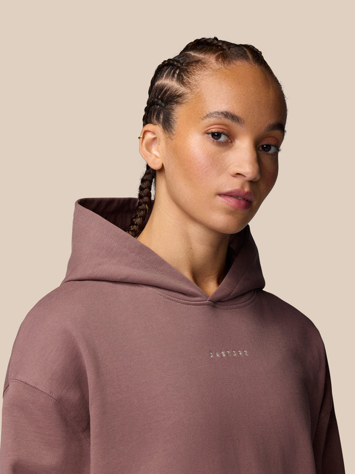 Close up of a female model wearing a mauve hoodie with hood up