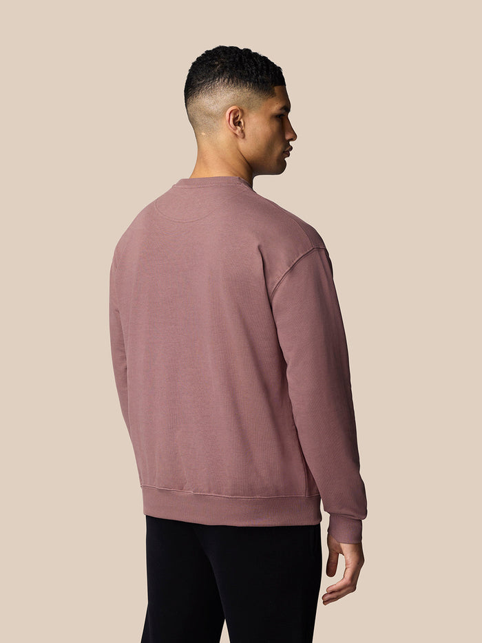 Back view of model in mauve oversized sweatshirt with ribbed cuffs and hem