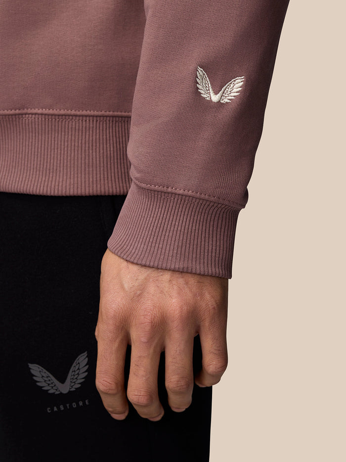 Close up of mauve Adapt Lifestyle Sweatshirt cuff showing white wing embroidery on the sleeve.