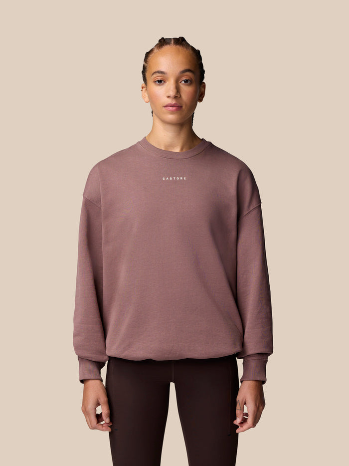 Model wearing mauve oversized sweatshirt with crew neckline and small chest logo