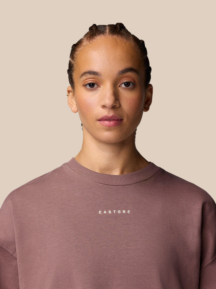Female model in mauve Adapt Lifestyle Sweatshirt with crew neck and Castore logo on the chest.