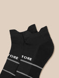 Close-up view of black athletic socks with ribbed cuffs against a beige background