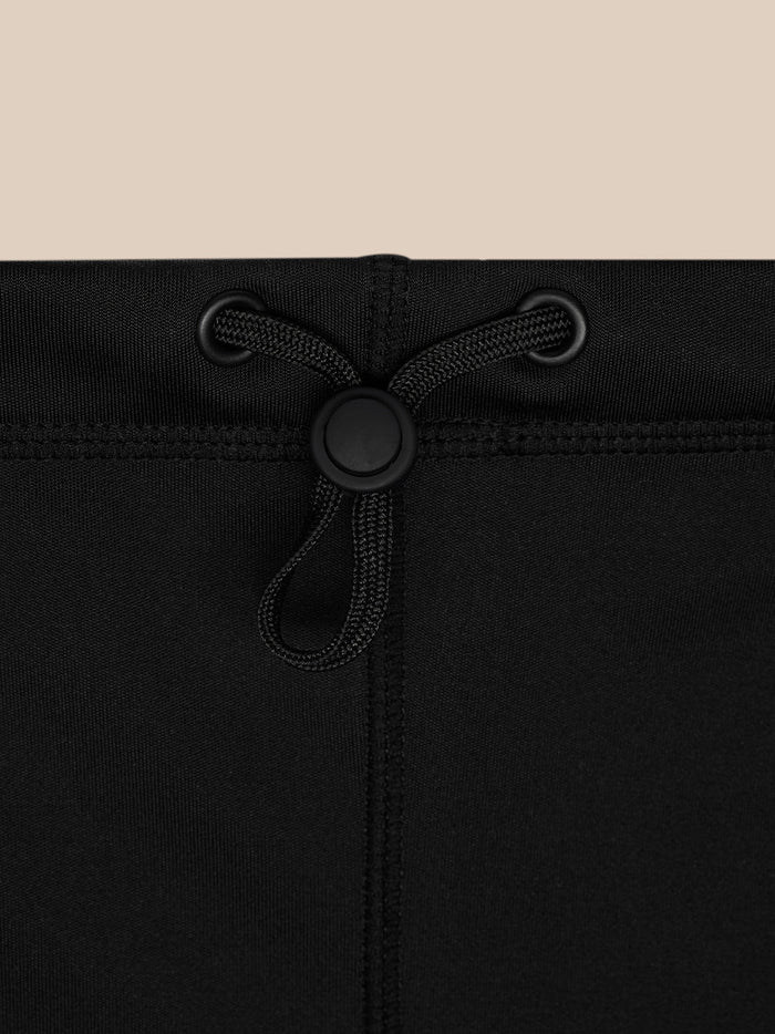 Top edge detail of black snood with a round cord lock and drawstring through eyelets