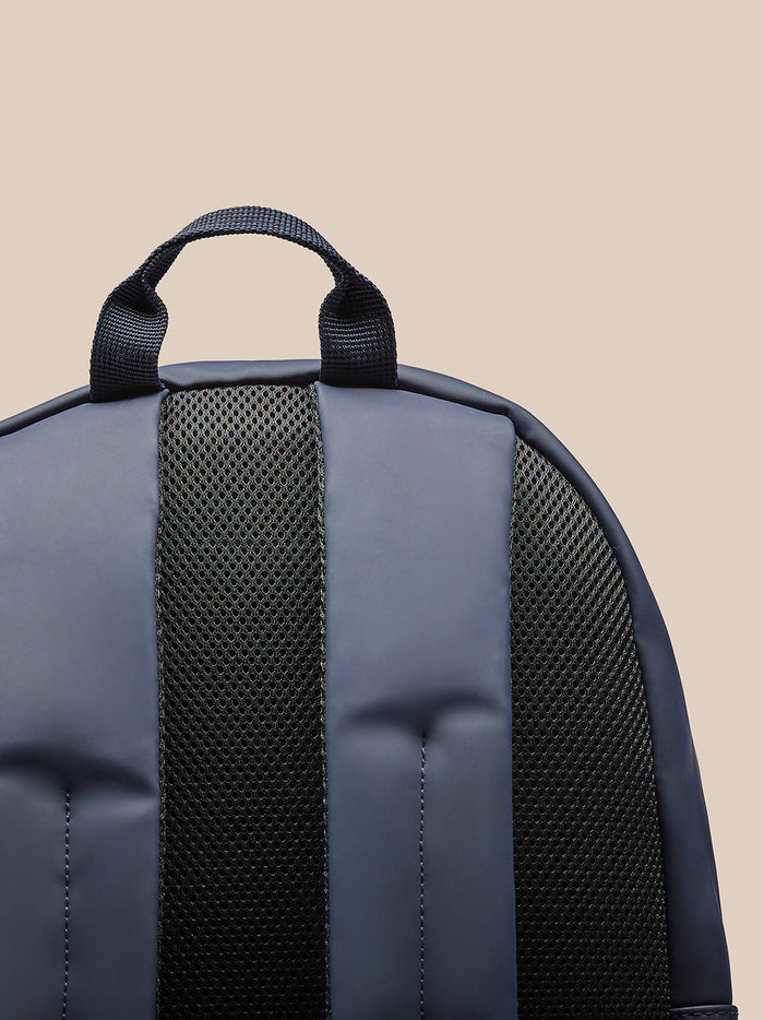 Close up of navy backpack top with carrying handle and padded back panel