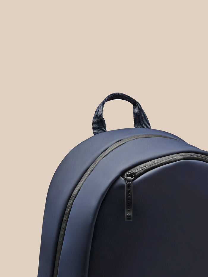 Navy backpack with top carry handle and front zipper featuring CASTORE branding