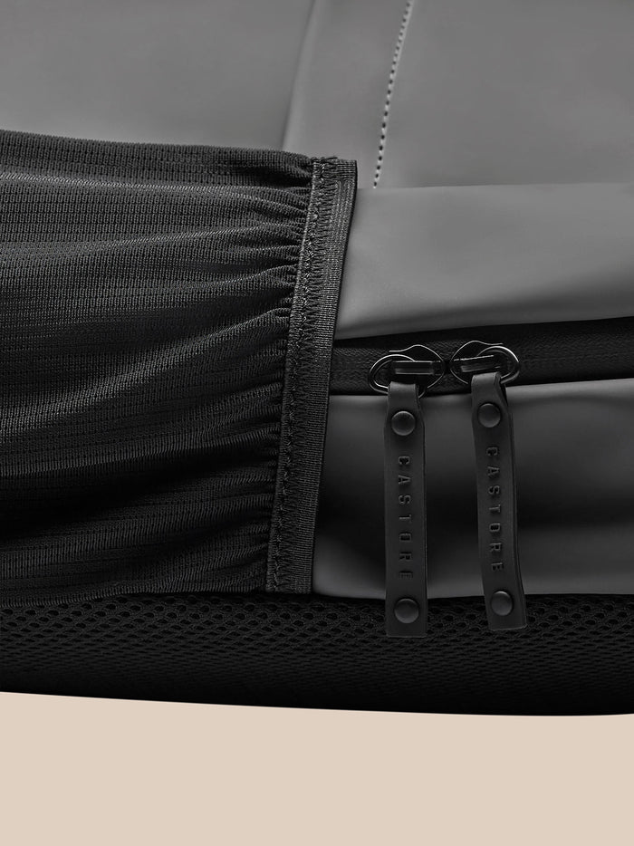 Detail of zipper area on charcoal backpack with dual CASTORE branded zipper pulls and mesh trim