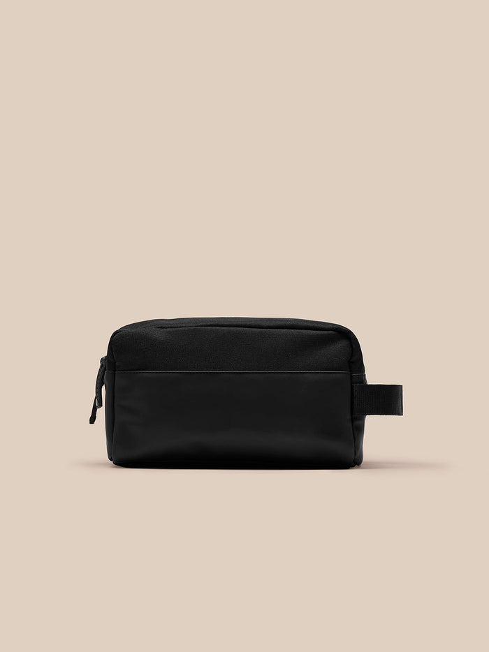 Close up of black Castore wash bag showing side strap and top zipper.