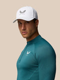 Male model wearing a white Castore cap with logo and teal athletic top