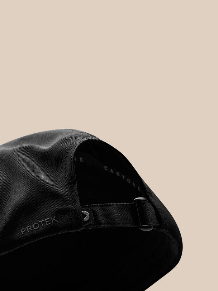 Close-up of back strap area on black cap with Protek branding visible