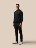 Male model in a black long sleeve zip top and matching golf trousers with white shoes