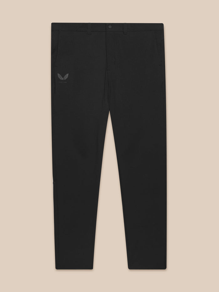 Flat lay view of black golf trousers with front button, belt loops, and a Castore logo on the left hip.