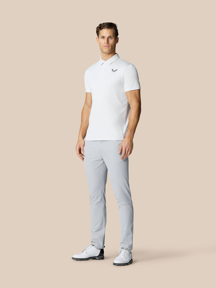 Full-length view of a man in light grey Golf Club Trousers with a woven belt and white polo shirt.