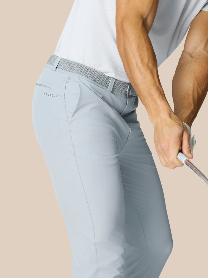 Close-up of mid grey Golf Club Trousers with a woven belt and Castore branding on the back pocket.