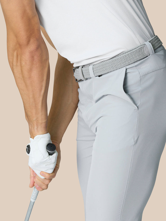 Side view of light grey golf trousers with a woven belt and ProTek branding at the waist on a model.