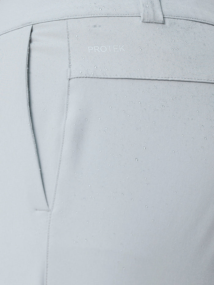 Close up of the back pocket area on light grey golf trousers, featuring ProTek branding and water droplets.