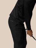 Side view of a man in black golf trousers holding a golf club with Castore branding on the back pocket