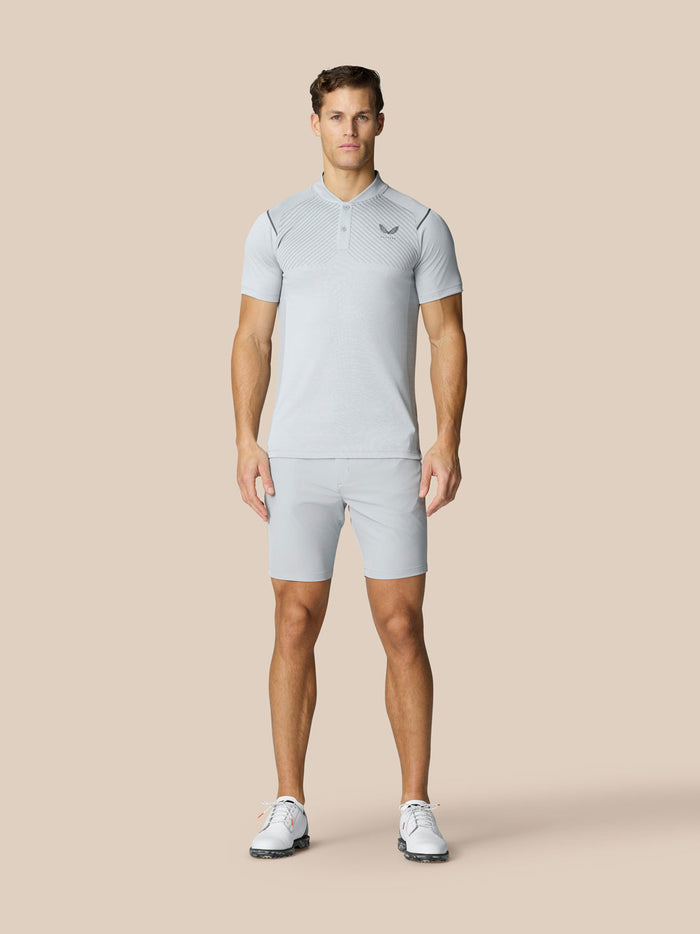 Full-body view of a man in light grey golf polo and matching shorts with a braided belt