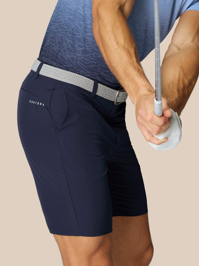 Close-up of navy Golf Club Shorts with a light gray braided belt and Castore branding on the thigh.