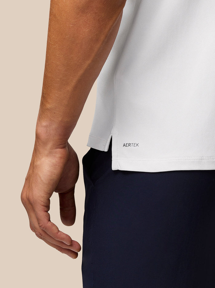 Close up of the back hem on a white Golf Club Essential Polo showing Aertek branding.