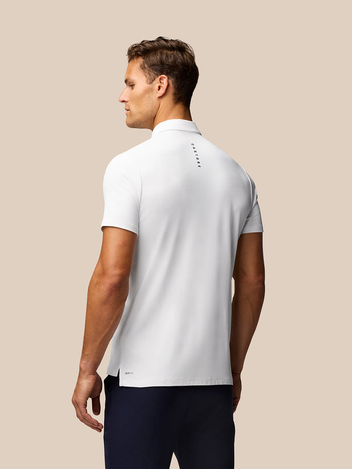 Back view of a male model in a white Golf Club Essential Polo with Castore branding along the upper back.